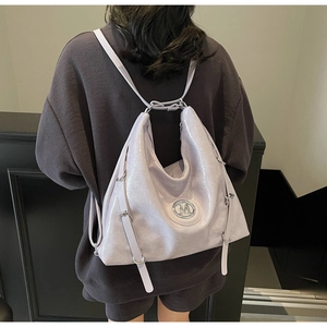 Détail du sac à dos en cuir verni lilas avec logo M en métal et bretelles réglables