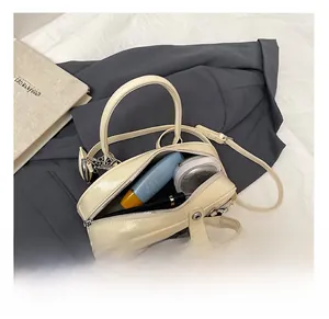 Détails de l'intérieur du sac crème montrant les essentiels quotidiens et la finition brillante