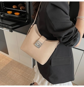 Detail view of a beige minimalist shoulder bag with a square interlocking silver buckle