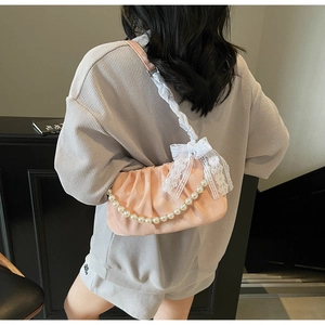 Detail of pink ruched cloud bag featuring white lace bow and large pearl chain decoration