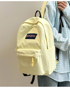 Detalle de la mochila ligera color crema con bolsillo frontal y bolsillo lateral