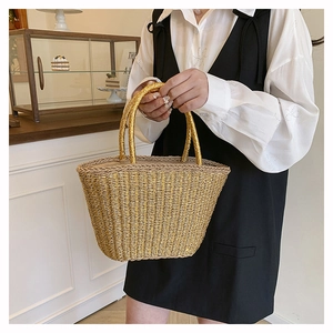 Detailed close-up of a woven gold bucket bag with sturdy handles in a chic cafe setting