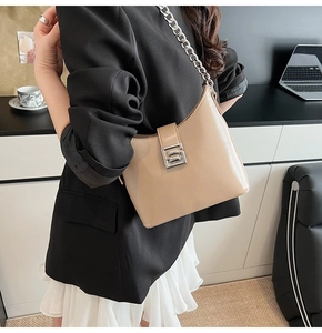 Detail of beige glossy shoulder bag with silver chain strap and metallic square buckle
