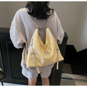 Détail d'un grand sac à dos en cuir verni beige avec logo M et boucles argentées
