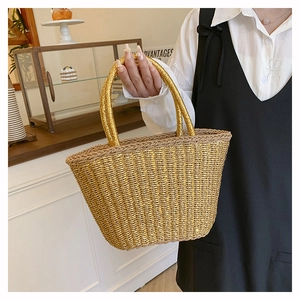 Detail view of a metallic golden woven bucket bag with elegant round handles for summer
