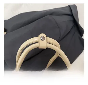 Détail du sac bowling en cuir crème avec double poignées et rivets métalliques fixés