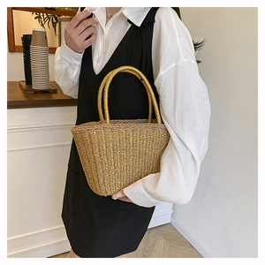 Chic gold woven tote bag held by a model in a cafe setting for a summer resort style