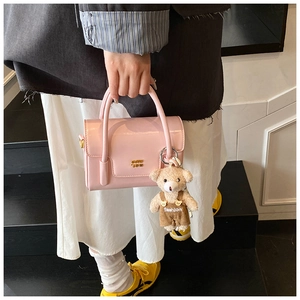 Details der hellrosa Handtasche aus Lackleder mit Goldlogo und Plüschbär-Anhänger