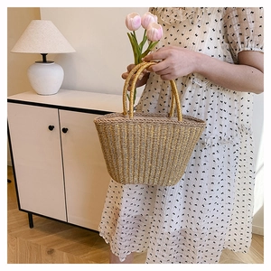 Detail of woven straw tote bag with golden handles and chic textured pattern