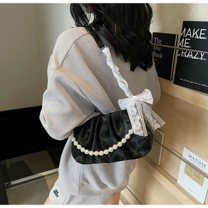 Detail of black pleated cloud bag with pearl chain and white lace bow decoration