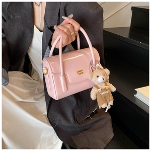 Detail der rosa Lacklederhandtasche mit glänzendem Finish und süßem Teddybär-Anhänger