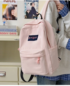 Detalle de la mochila rosa de lona ligera que muestra el bolsillo lateral y el frontal con cremallera