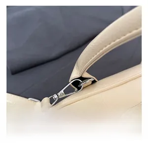 Vue détaillée du crochet métallique argenté et de la texture du cuir sur le sac crème