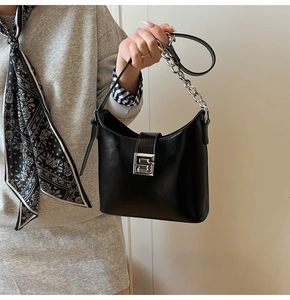Detail of black underarm bag featuring silver chain decor and square hollow metal buckle