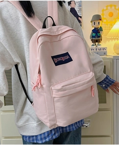 Detalle de una mochila rosa claro de gran capacidad con parche del logo de la marca