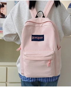 Detalle de la textura de tela rosa claro y el logotipo de la amplia mochila escolar
