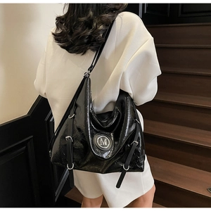 Vue détaillée du sac cabas en cuir verni noir avec logo M argenté et boucles métalliques