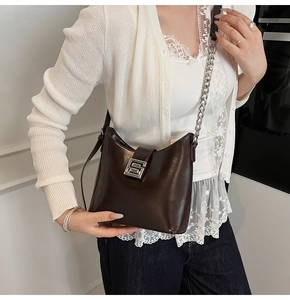 Detail of dark brown leather shoulder bag with silver metal buckle and chain strap