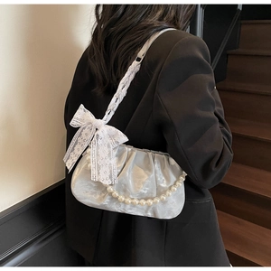 Detail of silver pleated cloud bag with lace bow, pearl chain and woven shoulder strap