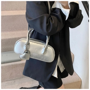 Détail d'un sac à main argenté avec pendentif coeur et logo Fashion Bags 1990