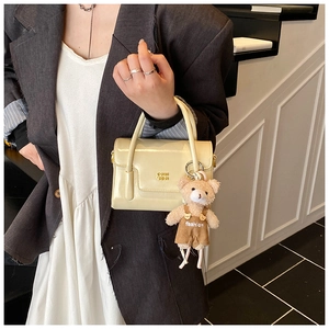 Detailansicht beige Handtasche mit Prägung und niedlichem Bären-Plüsch-Anhänger
