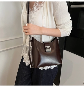 Detail of dark brown leather bucket bag with silver S-shaped buckle for daily commute
