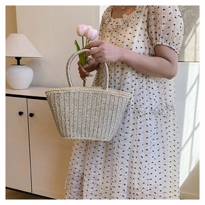 Detail of woven straw tote bag with silver circular handle styled in a home setting