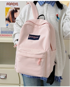 Detalle de mochila rosa claro de gran capacidad con bolsillo frontal y etiqueta logo