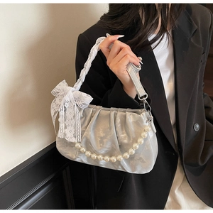 Close-up of ruched silver shoulder bag with lace bow and pearl chain detail