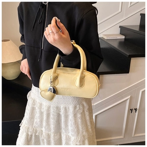 Détail d'un sac bowling jaune crème avec pendentif cœur et accents de ferrures argentées