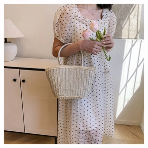 Detail of hand-woven beige straw tote bag with rounded handles for a casual summer look