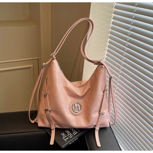 Détail du sac cabas en cuir texturé rose avec logo M argenté et sangles décoratives sur le côté