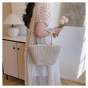Detailed view of woven straw tote with circular handle on a minimalist indoor background