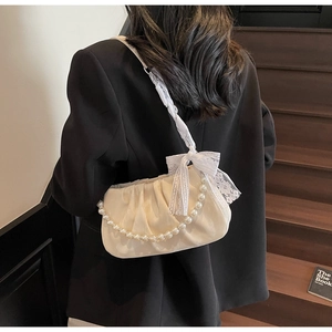Detail of white pleated cloud bag featuring elegant pearl chain and lace bow strap