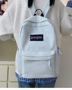 Vista posterior de una mochila casual azul claro con etiqueta de marca azul marino para estudiantes