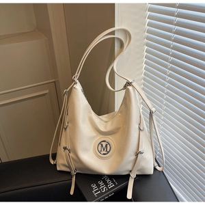 Gros plan du sac crème avec plaque argentée M et texture en cuir souple plissé élégant