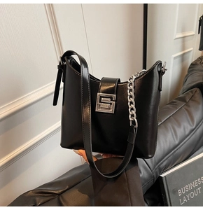 Detail of minimalist black underarm bag with silver chain and geometric metal buckle