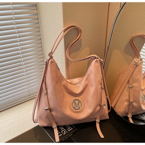 Détail du sac cabas rose poudré montrant la texture plissée et le logo M en métal argenté