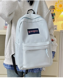 Primer plano de una mochila de lona azul claro con bolsillo frontal y etiqueta sobre mesa