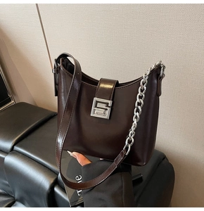 Close-up of dark brown hobo bag with silver metal chain and leather shoulder strap