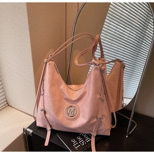 Gros plan sur la texture cuir plissé rose et le logo M métallique du grand sac fourre-tout