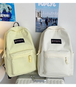 Primer plano de mochilas minimalistas de lona en amarillo y crema sobre una maleta