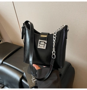 Detail of black underarm bag with silver square S-buckle and decorative chunky chain strap