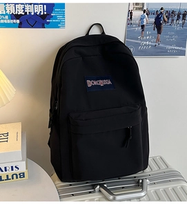 Detalle de una mochila grande de nailon negro con bolsillo frontal en una maleta plateada