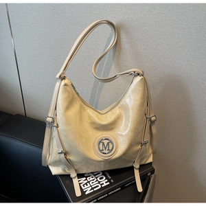 Détail du sac hobo beige brillant avec texture froissée et emblème M en métal