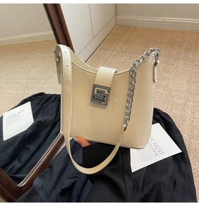 Detail of cream white leather bucket bag with silver geometric buckle and chain strap