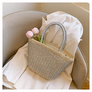 Close-up of woven straw tote bag with silver metallic threads and rounded silver handles