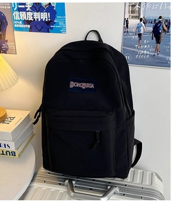 Primer plano de mochila de lona negra con parche bordado y bolsillos para estudiantes