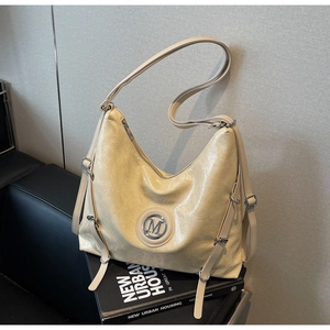 Détail du sac hobo crème avec texture en cuir brillant plissé et logo M en métal