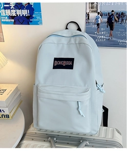 Primer plano de una mochila azul claro sobre una maleta con parche de marca